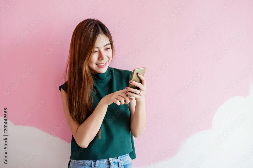 Portrait of Young Woman Smiling while using Smart Phone at the wall. Lifestyle of Modern Female Portrait of Young Woman Smiling while using Smart Phone at the wall. Lifestyle of Modern Female
