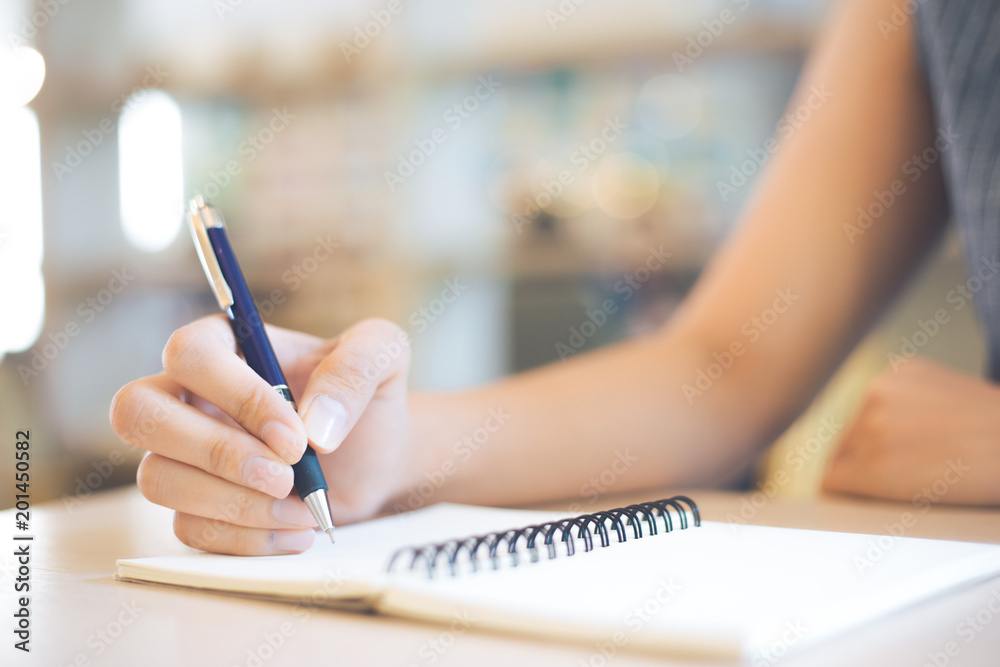 Business woman hand is writing on a note pad with a pen in office.