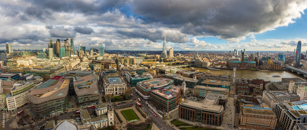 London, England - Panoramic skyline view of London. This view includes the skyscrapers of Bank District, Tower Bridge, Shard skyscraper and Millennium Bridge. Beautiful dramatic clouds and sunshine