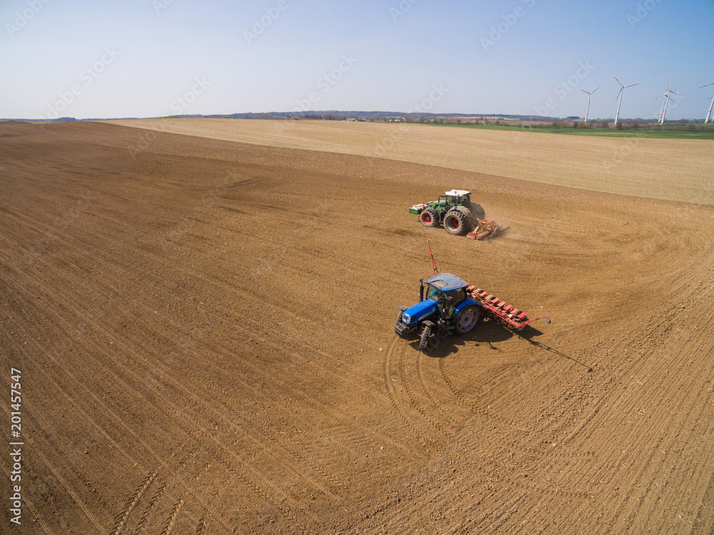 aerial view - two tractors working on the agricultural field plowing and sowing in the field 