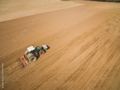  aerial view - tractor plows a agricultural field in spring and prepares it for sowing