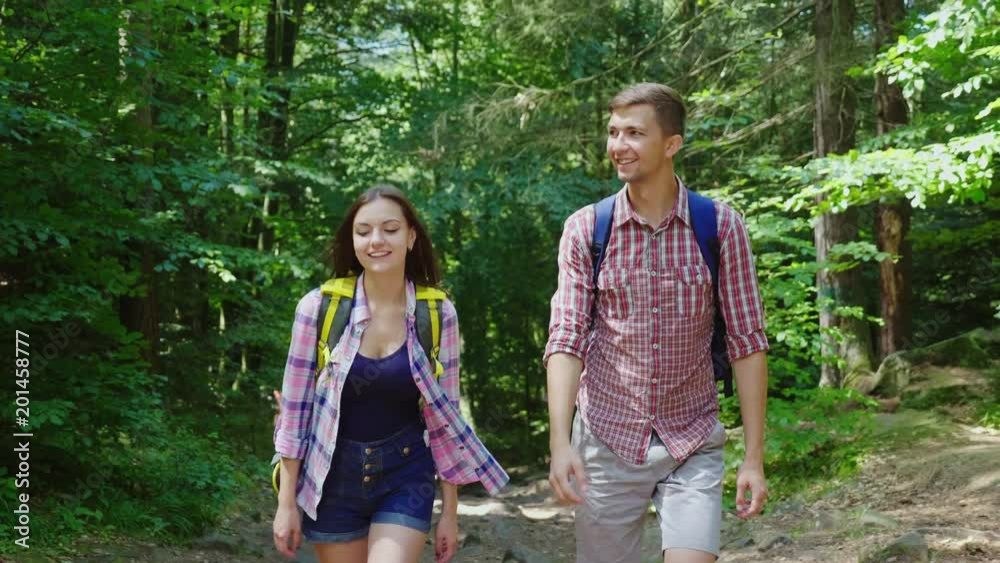 A man and a woman are walking in the woods, communicate on the move, have a good time on the march A man and a woman are walking in the woods, communicate on the move, have a good time on the march