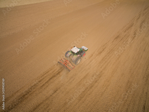 aerial view - tractor plows a agricultural field in spring and prepares it for sowing