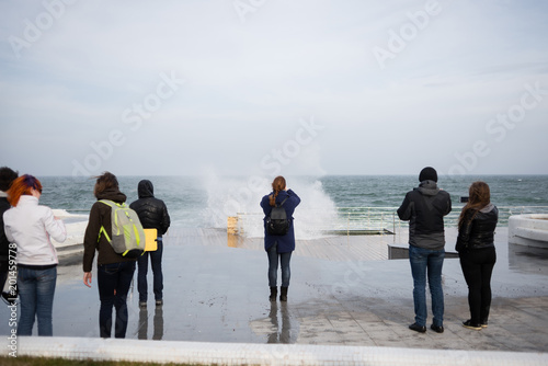 people stand on the beach by the sea during a storm