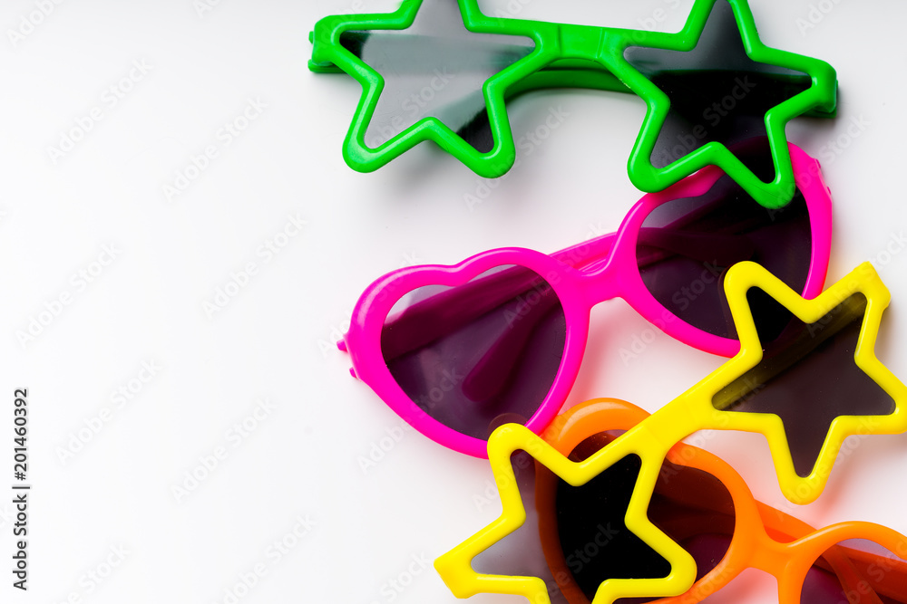 Children's sunglasses in bright colors and various forms on white background with copy space. Kid's party concept Children's sunglasses in bright colors and various forms on white background with copy space. Kid's party concept