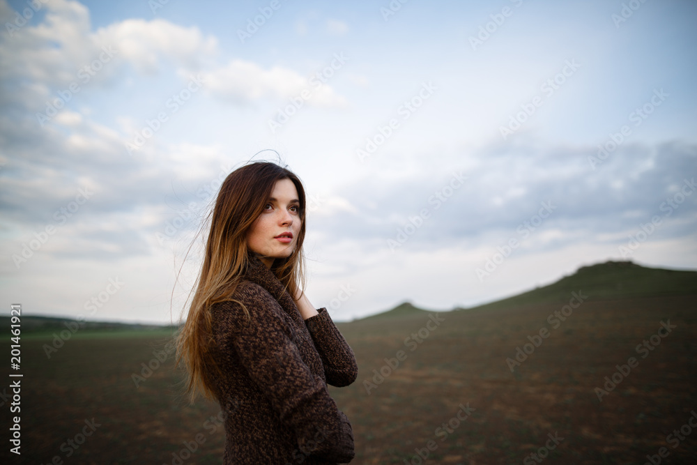 Beautiful brunette lady in soil field at sunset. Happy beautiful woman in meadow. Beautiful carefree woman in fields. Portrait of beautiful young woman