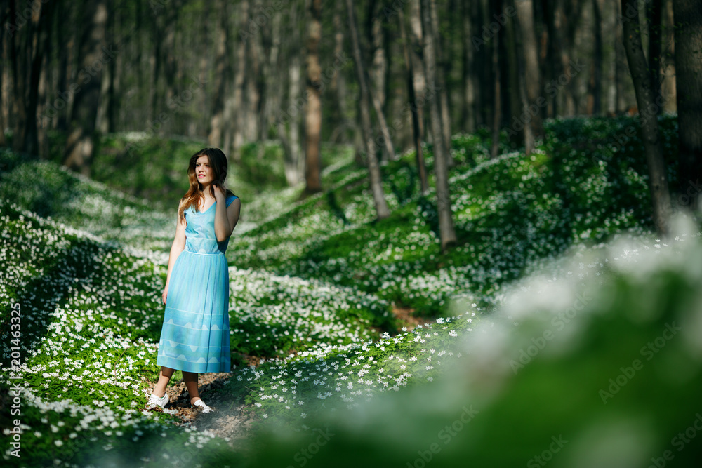 Relaxing woman at nature. Happy pretty young woman enjoying smell flowers over spring forest background Relaxing woman at nature. Happy pretty young woman enjoying smell flowers over spring forest background