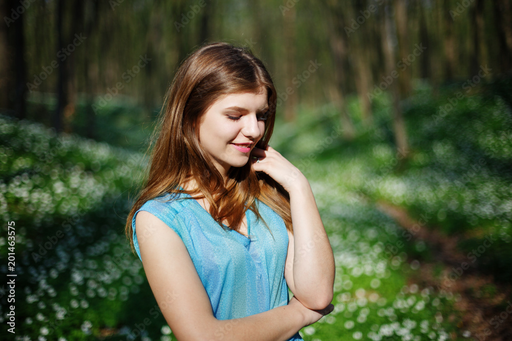 Relaxing woman at nature. Happy pretty young woman enjoying smell flowers over spring forest background Relaxing woman at nature. Happy pretty young woman enjoying smell flowers over spring forest background