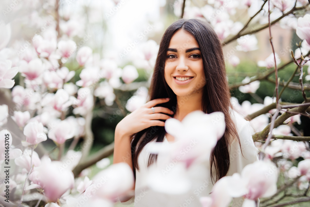 Young pretty woman portrait near flower of blossom magnolia tree. Spring time Young pretty woman portrait near flower of blossom magnolia tree. Spring time