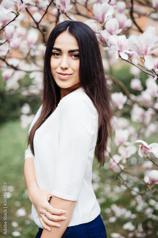 Outdoor portrait of a young beautiful woman near magnolia tree with flowers. Outdoor portrait of a young beautiful woman near magnolia tree with flowers.