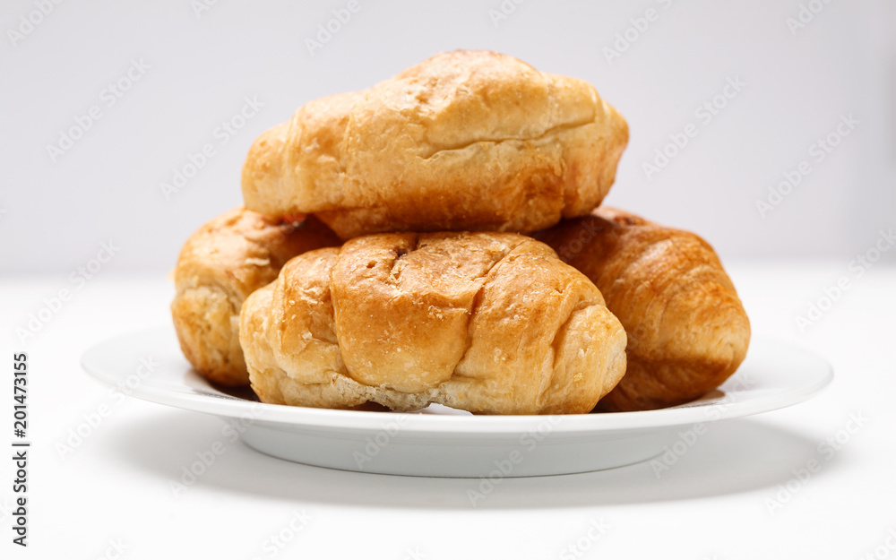 Fresh croissant in a white plate on a white table