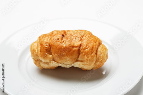 Single fresh croissant in a white plate on a white table © Glevalex