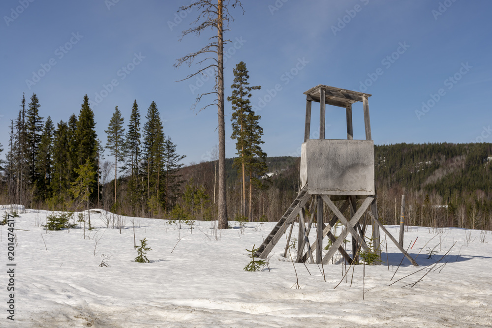 Hunting tower used fore moose hunting, on a winter day with snow and forest and blue sky in background Hunting tower used fore moose hunting, on a winter day with snow and forest and blue sky in background