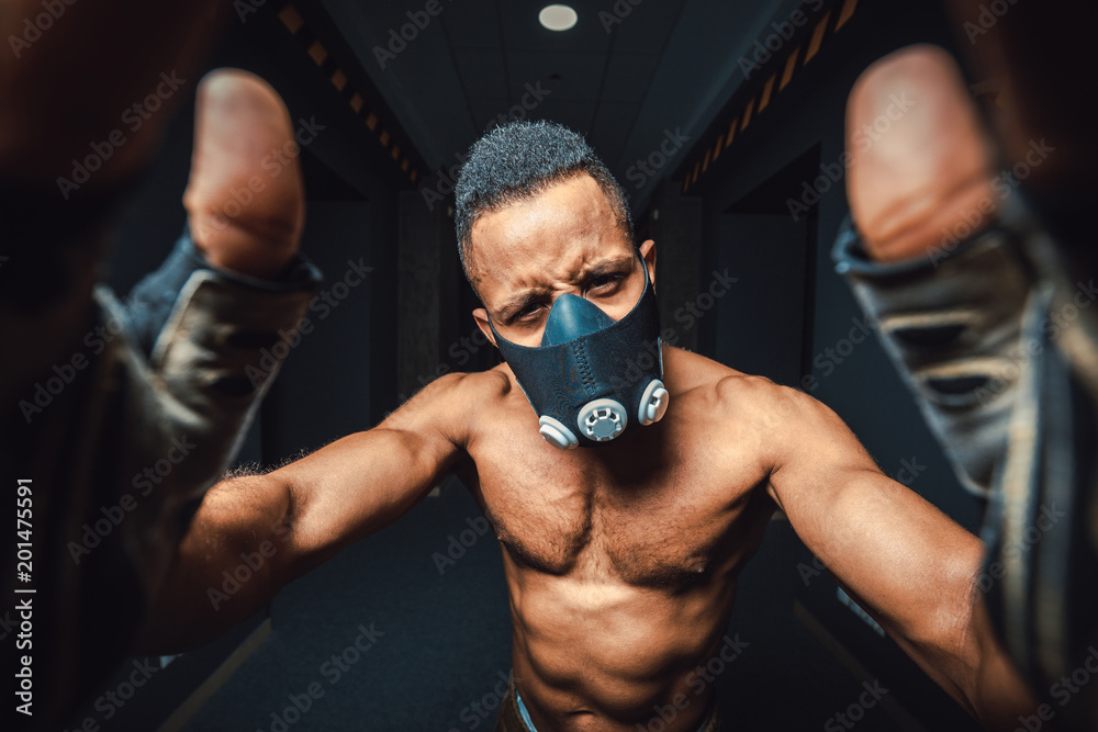 african american man in mask doing selfie in gym. black man looking at camera and holds hands on camera