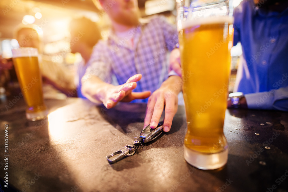 Drunk man taking car key from pub table with a draft beer in front. Close up  focus view of key and hands. Stock Photo | Adobe Stock