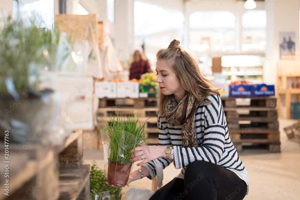 Woman checking fresh herbs at organic grocery store