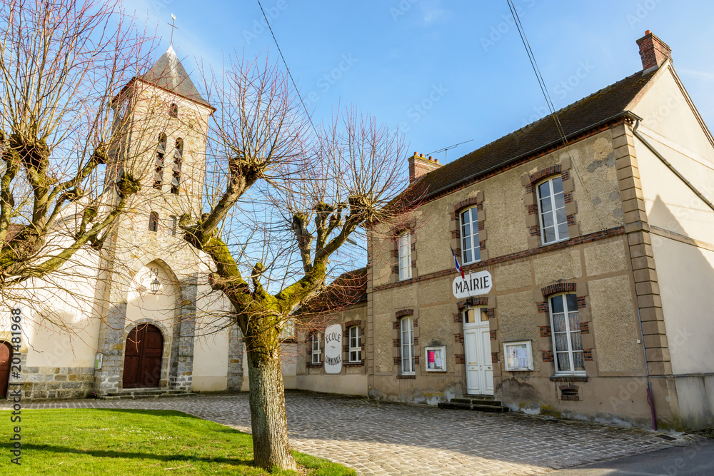 The church square of the small french village of Beauvoir in the department of Seine-et-Marne, 60 kilometers south-east to Paris, with its town hall, church and elementary school in between at sunset.