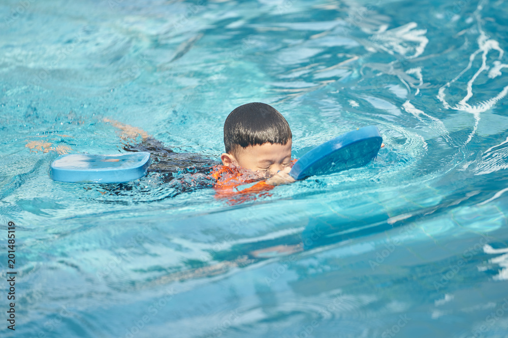 boy practise swimming with foam pad floater in water