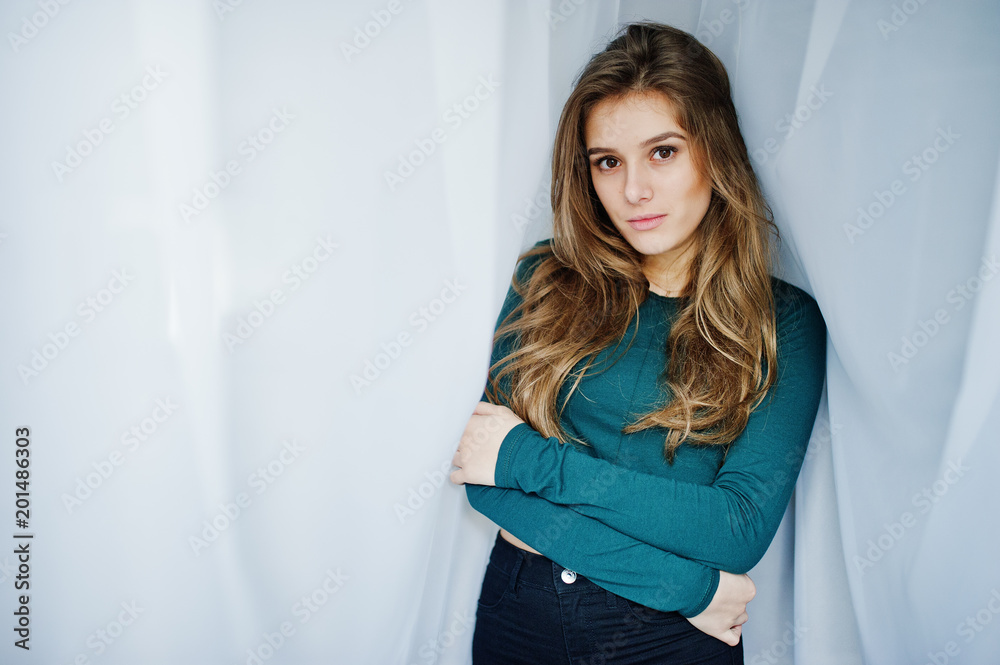 Handsome brunette girl wear on green, posing at curtains. Studio model portrait. Handsome brunette girl wear on green, posing at curtains. Studio model portrait.