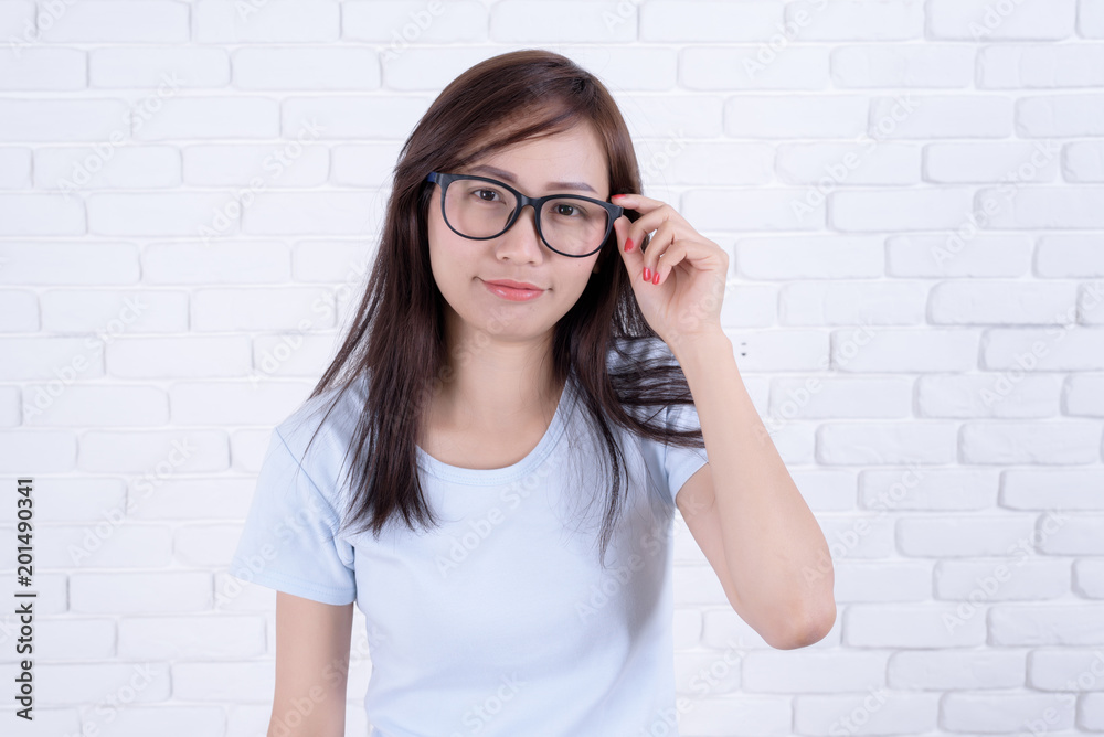 Smiling beautiful woman standing and points against a white brick wall. Girl at White Brick Wall Background. Smiling beautiful woman standing and points against a white brick wall. Girl at White Brick Wall Background.