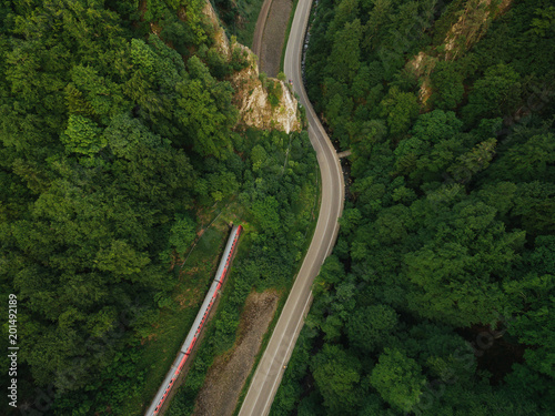 aerial view of road in beautiful mountain forest with train on railroad