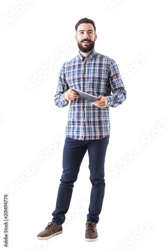 Happy smiling modern business man holding tablet computer looking at camera. Full body length portrait isolated on white background. 