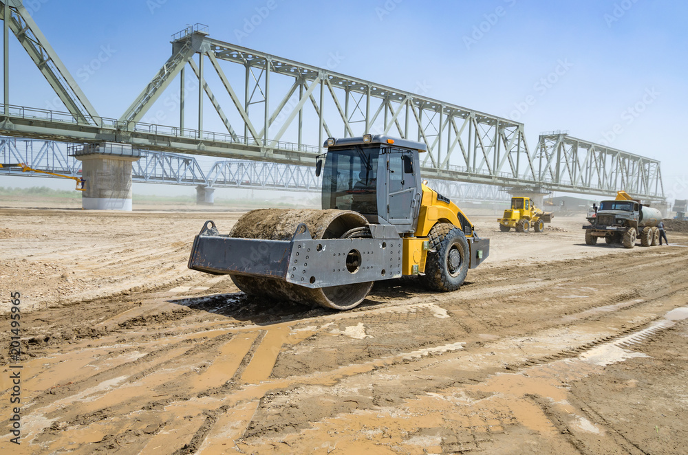Roller on earthworks on the background of construction Roller on earthworks on the background of construction