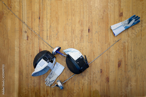 Fencing mask, gloves, swords and epees lie on the floor in the fencing gym photo