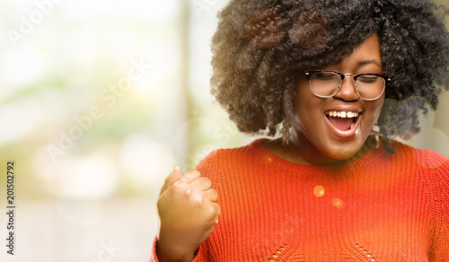 Beautiful african woman happy and excited celebrating victory expressing big success, power, energy and positive emotions. Celebrates new job joyful, outdoor © Krakenimages.com