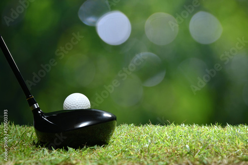 Piłka golfowa na zielonej trawie przygotowywającej uderzającą na pola golfowego tle