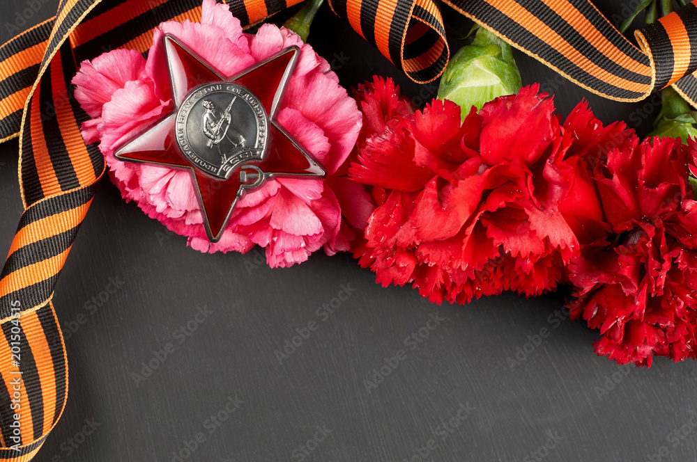 Concept background of May 9 russian holiday Victory Day. Red carnations, St. George's ribbon and order of the Red Star