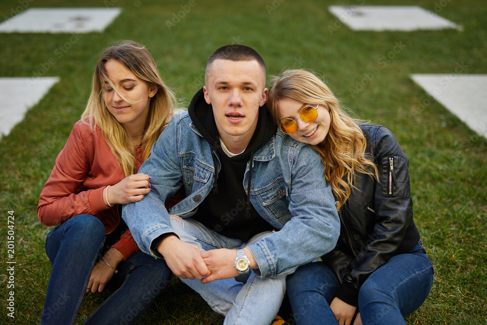 Boy with two girls on the green grass talking and smile to camera Boy with two girls on the green grass talking and smile to camera