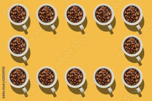 Cup concept. White cups with coffee beans on yellow background. Creative style.