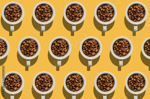 Pattern. Cup with coffee beans concept. Group of white cups on yellow background. Creative style.
