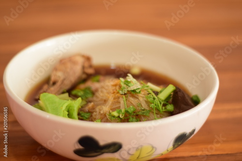 Close up Braised chicken noodle soup on wooden table ready to eat