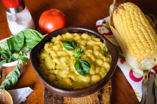 Classical Chilean food white beans in corn sauce in a clay bowl closeup. Porotos con mazamorra in spanish. photo