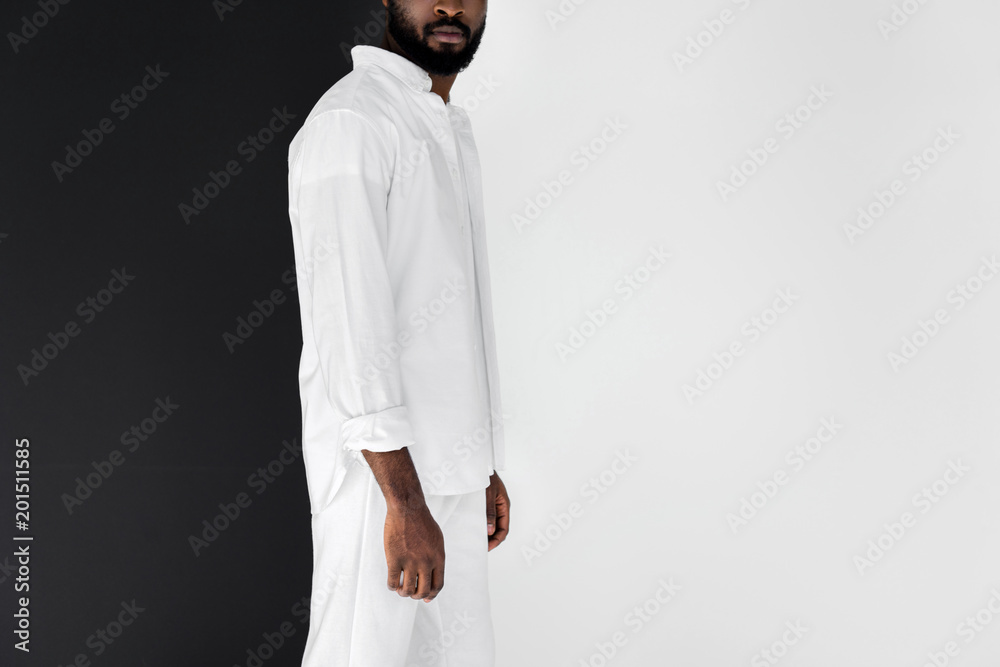 cropped image of stylish african american man in white clothes on black and white cropped image of stylish african american man in white clothes on black and white