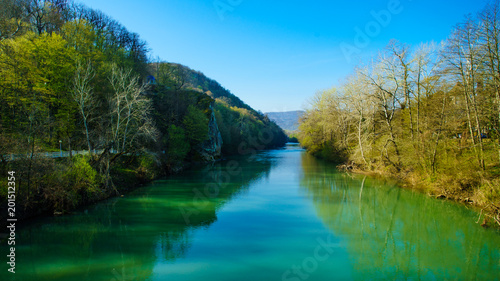 Blue river flowing across green forest © EwaStudio