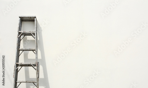 aluminum foldable ladder and the shadow at white cement wall