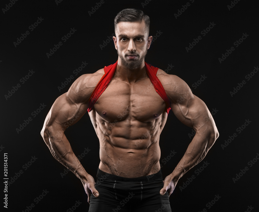 Cute young sports man in red t-shirt shows relief abdominal muscles in gym Cute young sports man in red t-shirt shows relief abdominal muscles in gym