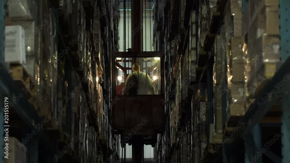 Man reversing and descending forklift in aisle of warehouse. Man reversing and descending forklift in aisle of warehouse.
