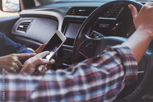 Two people using map on smart phone in a car for travel. photo