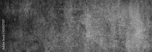 Textur einer fast schwarzen Betonwand in XXL-Größe als Hintergrund, auf die ein wenig Licht fällt
