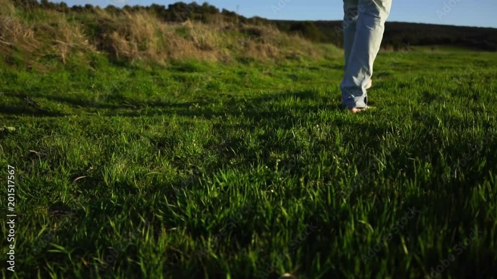 Hombre joven caminando descalzo por la hierba 