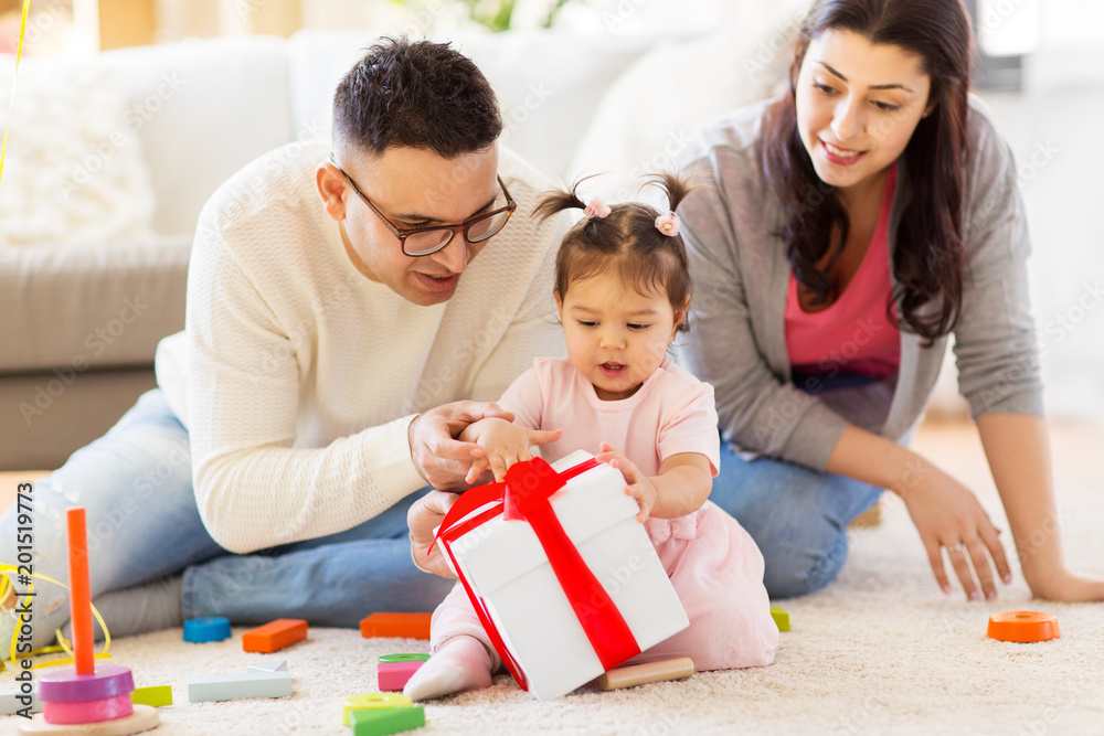 family, holidays and people concept - mother, father and happy little daughter with gift box at home birthday party family, holidays and people concept - mother, father and happy little daughter with gift box at home birthday party