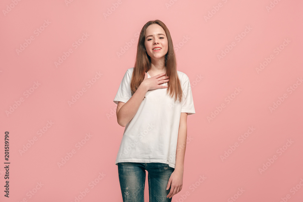 The happy teen girl standing and smiling against pink background. The happy teen girl standing and smiling against pink background.