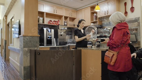 Panning shot of a senior woman buying a pastry for her husband photo