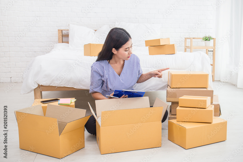 Startup small business entrepreneur SME, asian woman writing on clipboard. Portrait young small business owner at warehouse home office, online marketing packing delivery, SME e-commerce concept