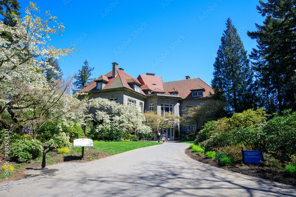 Pittock Mansion, view on the house surrounded by trees from the garden on a beautiful sunny spring day, Portland