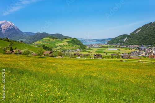 A springtime view from the foot of Mt. Stanserhorn in the Swiss canton of Nidwalden, summit of Mt. Pilatus, Lake Lucerne and buildings of the town of Stans in the background